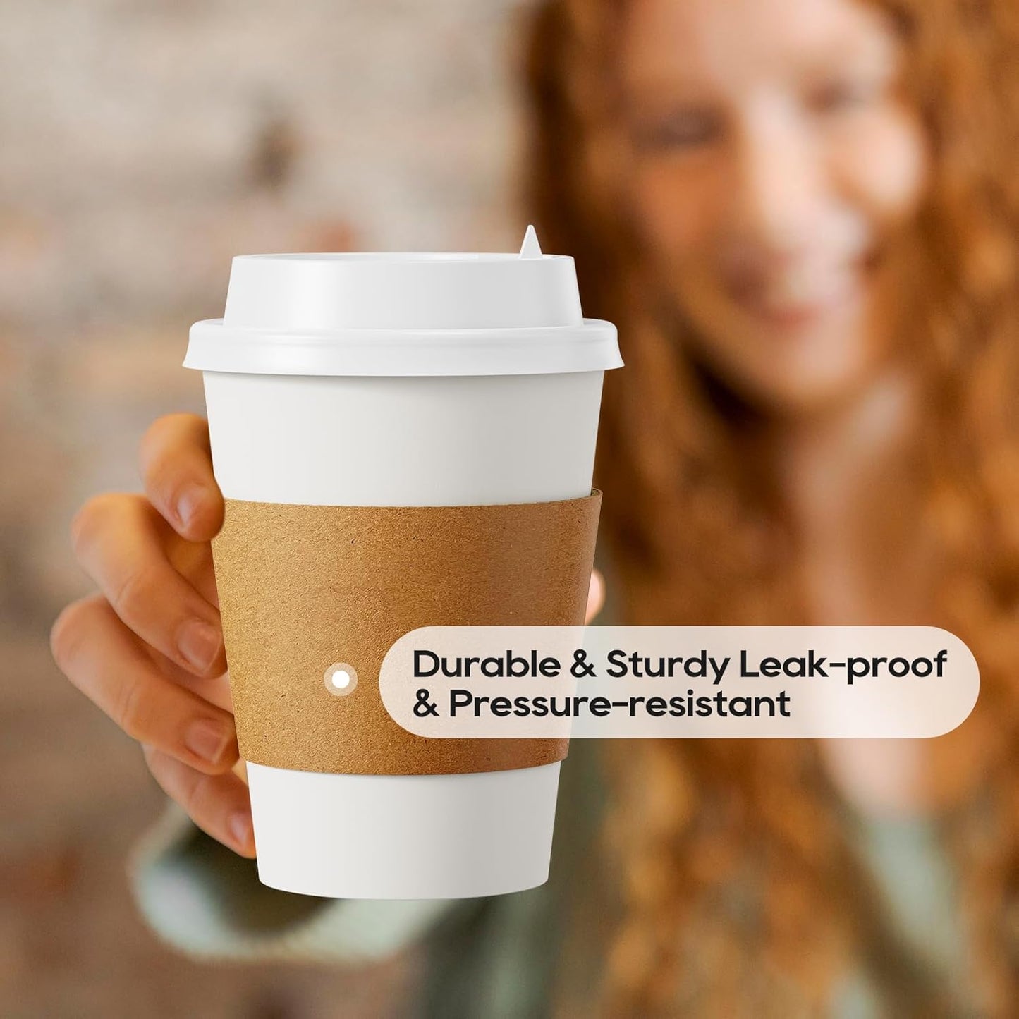 A person holding a disposable coffee cup with a lid and kraft sleeve, emphasizing the cup's durability and leak-proof feature.